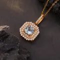 Gedetailleerd macrozicht op een elegante vierkante blauwe edelsteen hanger met dubbele halo-ring. - Natuurlijke Topaas / Goud
