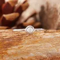 Primo piano di un anello minimalista in argento S925 con perla su pietra rustica - Perline artificiali