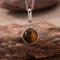 Detailed view of a round polished tiger's eye pendant on a 925 sterling silver necklace chain - Natural Tiger's Eye Style (N470) / Silver