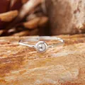 Primo piano di un anello in argento con gemma rotonda incastonata su legno naturale - Acquamarina