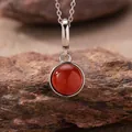 Exquisite close-up of a round red agate pendant necklace resting on a natural rock texture - Natural Red Agate Style (N470) / Silver