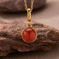 Close-up of a natural red agate pendant with gold-plated sterling silver chain on rock. - Natural Red Agate Style (N470) / Gold
