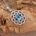 Close-up of blue topaz pendant necklace with halo of small crystals on rock background - Natural Topaz Necklace