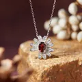 Macro shot of a silver daisy necklace featuring an oval red gemstone and clear crystals. - Necklace / Garnet
