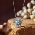 Detailed close-up of a silver daisy pendant necklace with a brilliant blue oval gemstone. - Necklace / Topaz