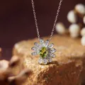 Detailed close-up of a silver daisy necklace pendant featuring a green oval gemstone center - Necklace / Peridot