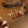 Macro detail of gold hoop earrings with pink ruby gemstones on a natural branch - Natural Ruby Hoop