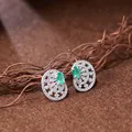 Macro detail of vintage hollow S925 silver stud earrings with oval emerald-green gemstones. - Natural Emerald Style