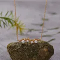 Close-up of natural pearls set in a textured gold-plated sterling silver bar necklace. - Pearl Necklace / Gold