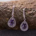 Close-up of elegant teardrop earrings with purple amethyst stones and a silver halo - Natural Amethyst