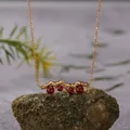 Close-up of S925 silver garnet necklace with mountain-shaped pendant on a rock - Garnet Necklace / Gold
