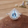 Close-up of pear-shaped blue gemstone ring with double halo in S925 silver setting. - Topaz