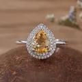 Macro view of a pear-shaped citrine halo ring with sparkling side stones. - Citrine