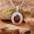 Dettaglio macro di un ciondolo di lusso in granato rosso ovale con doppio contorno di cristalli. - Collana Granato Naturale