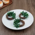 Detailed view of handmade vine napkin rings with green leaves on a white plate - Smilax Glabra Vine Style