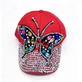 Close-up of vibrant red baseball cap with colorful rhinestone butterfly and studded brim. - Adult, Hat Circumference 58cm Adjustable / Red