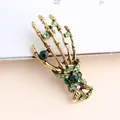 Vintage skeleton hand brooch with green rhinestones in a stylish antique gold finish - Green Skeleton Hand / Green