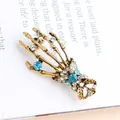 Vintage gold skeleton hand brooch with sparkling blue and white rhinestones decoration - Lake Blue