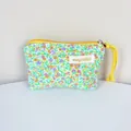 Detailed macro view of the small floral cotton pouch showing the brand label and yellow zipper - Green Floral (Gold Label)