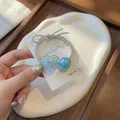 Vue détaillée d'un élastique argenté avec un pendentif cœur bleu et une perle irisée - Cœur Bleu Nœud Papillon (A025-2) / Bleu