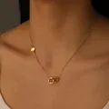 Close-up of a gold titanium steel necklace featuring interlocking rings with a clover cutout - D116 Clover Double Ring Style / Gold