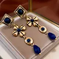Close-up of retro palace style long dangle earrings with gold metal and blue stones - Floral Design (11#) / Gold