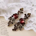 Detaillierte Nahaufnahme von Vintage-Palast-Ohrhängern mit tiefroten Kristallen und Gold-Finish - Blatt-Design (16#)