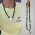 Detailweergave van een handgemaakte groene kralenketting met een natuurlijke witte schelphanger. - Eén maat / Groene ovale kraal schelphanger / 38+5cm / Groen
