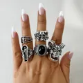 Gros plan d'un ensemble de cinq bagues punk vintage tête de mort et cercueil portées à la main - Bague 33629-S