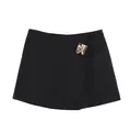 Detail view of the black skort's asymmetrical wrap front and chic gold buckle. - Black