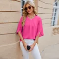 Detail of pink chiffon blouse with round neck and split sleeves in outdoor setting - Barbie Pink