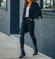 Detail view of a black fringe jacket paired with black ripped skinny jeans and boots - S / Tops / Black