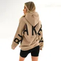 Back view detail of a beige oversized women's hoodie with black BLAKE lettering - S / Tops / Khaki