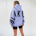 Detail view of a lilac oversized hoodie featuring a bold black BLAKE back print design. - Light Purple