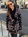 Woman wearing ethnic style fringed knit cardigan with belt on city street - S / Tops / Black Red