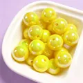 Close-up of 16mm yellow UV-plated acrylic beads with iridescent finish in a white dish - 1 Piece/Pack / Yellow