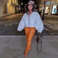 Detailed view of orange stretch PU leather pants with split hem and slim fit design. - S / Bottoms / Orange