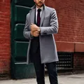 Modern man wearing a grey mid-length wool trench coat against a classic red brick wall - M / Tops / Gray