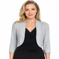 Detail view of a light grey cropped shrug cardigan worn over a black dress. - Gray