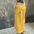 Dettaglio ravvicinato di un cardigan giallo con cappuccio a trecce e trama molto spessa. - Taglia S / Top / Giallo