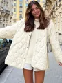 Detail of a cream quilted round neck jacket featuring wave patterns in a street setting - S / Tops / White
