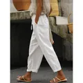 Detail view of white cotton linen cropped pants with drawstring waist on a model outdoors. - S / Bottoms / White