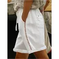 Detailed close-up of women's white leisure shorts featuring hollow lace side stitching. - S / Bottoms / White
