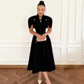 Elegant black vintage dress with stand collar and capelet design on a model in a room. - S / Top And Bottom / Black