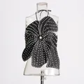 Detailed view of black halter top with pearl embellishments and petal design on clear mannequin. - M / Tops / Black