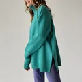 Close-up side view of a green loose-fit turtleneck knit sweater with unique side slit details - S / Tops / Emerald Green