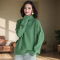 Κομψή γυναίκα με άνετο πράσινο oversized πλεκτό πουλόβερ με ζιβάγκο σε φωτεινό δωμάτιο. - Σμαραγδί