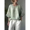 Close-up of loose-fitting green linen-textured shirt with a relaxed round neckline - S / Tops / Light Green