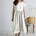 Close-up detail of a white loose cotton linen midi dress with a pleated waist design - Off White