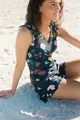 Sleeveless floral print V-neck romper with ruffle details shown on a sandy beach - XS / Top And Bottom / Blue Floral